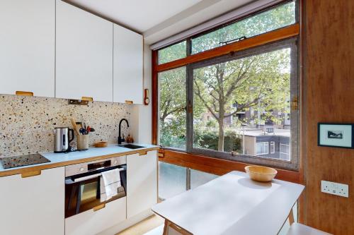 a kitchen with white cabinets and a large window at Spacious 1 bedroom apartment in Kennington in London