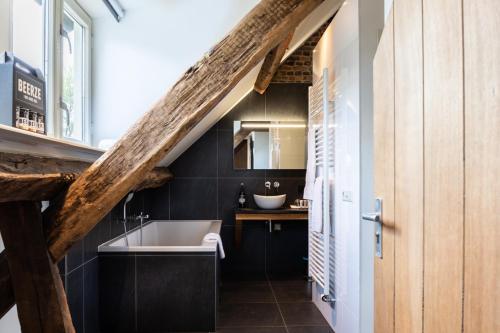 a bathroom with a sink and a bath tub at Beerze Brouwerij Hotel in Vessem