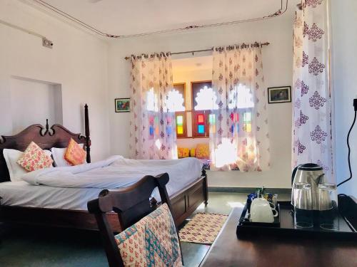 a bedroom with a bed and a desk and window at Deogarh Hills A Village Experience Property in Kaunthal