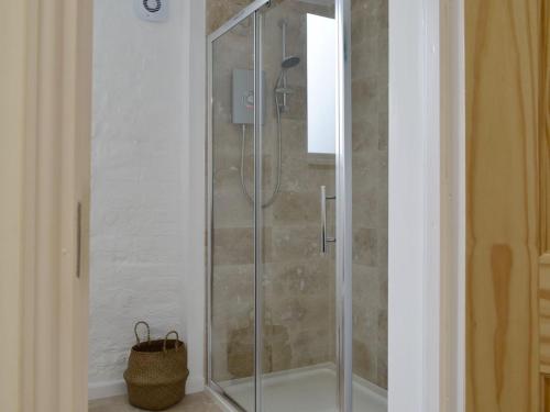 een douche met een glazen deur in de badkamer bij The Hay Barn in Barnby