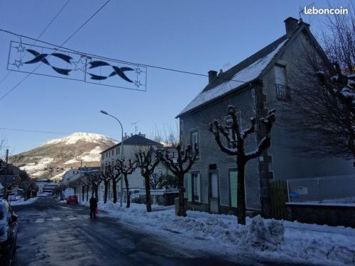 a snow covered street in a town with a mountain at Le Sancy, appart T2, 4 pers, centre ville du Mont Dore in Le Mont-Dore