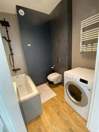 a bathroom with a washing machine and a toilet at Nowe 3 pokojowe mieszkanie z dużym tarasem in Kalisz