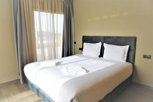 a large bed with white sheets and a window at Dominium Residence in Agadir