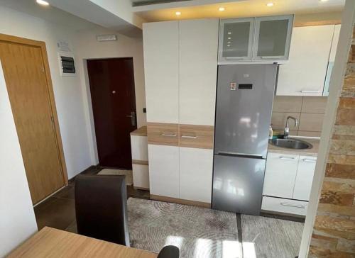 a kitchen with white cabinets and a stainless steel refrigerator at Milmari Resort Lux H-1 in Kopaonik