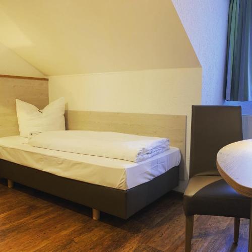a bedroom with a bed and a table and a chair at Hotel Waibstadter Hof in Waibstadt