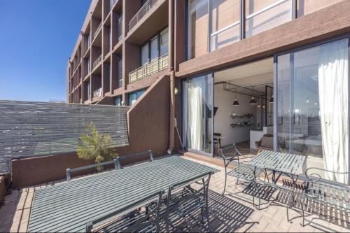 eine Terrasse mit Bänken und Tischen auf einem Gebäude in der Unterkunft Homely Studio Apartment in Cape Town in Kapstadt