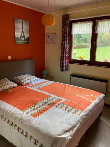 a bedroom with a bed with an orange wall at Maison Catharina in Vielsalm