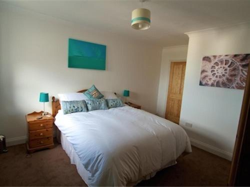 - une chambre avec un grand lit blanc et une table de nuit dans l'établissement Jurassic Apartments, à Weymouth