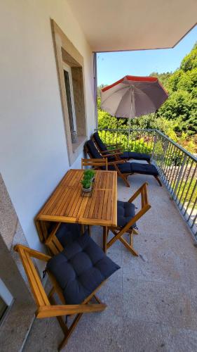 a patio with a table and chairs and an umbrella at Casa Barca Velha in Ponte da Barca