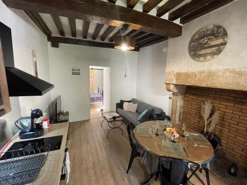 a living room with a table and a fireplace at Le Petit Duc in Dijon