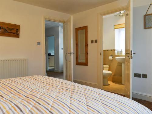 a bedroom with a bed and a bathroom with a toilet at Belah Barn in Kirkby Stephen