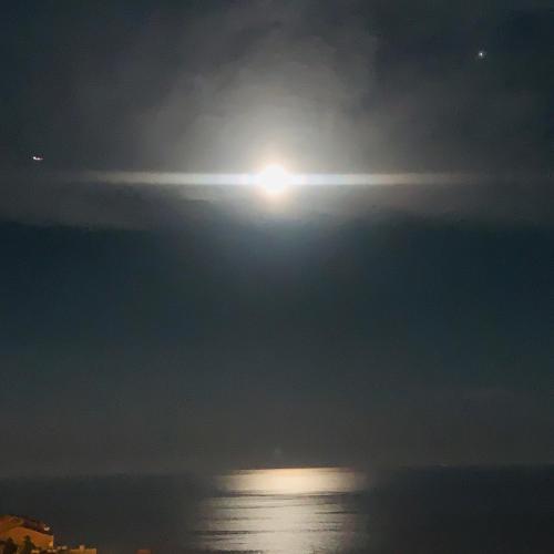 a full moon rising over the ocean at night at SARA RIVIERA Costa Plana in Cap d'Ail