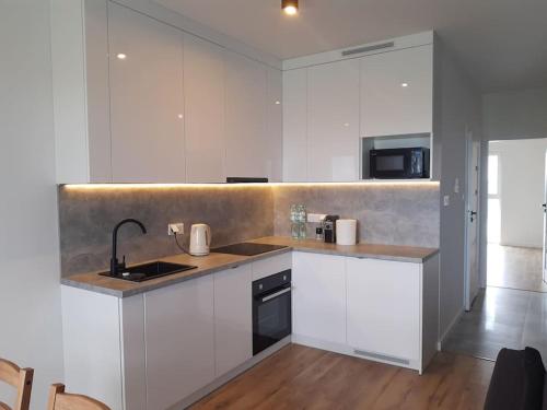 cocina con armarios blancos, fregadero y encimera en NEW APARTMENT Wołyńska - przestronny, z widokiem, czysto, parking, balkon, en Rzeszów