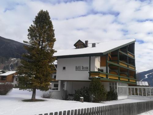a building with a tree in the snow at Hotel Brandl in San Candido