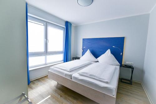 a bedroom with a bed with white sheets and pillows at Beach Lodge BL03 in Cuxhaven