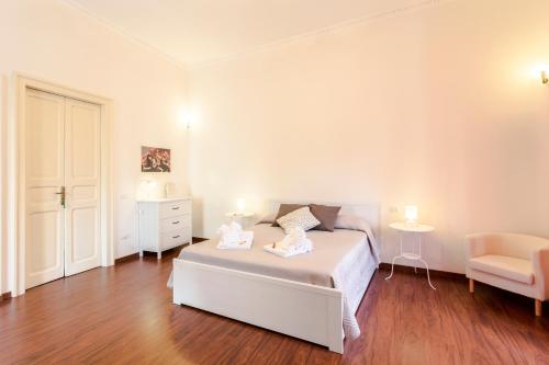 a white bedroom with a bed and a chair at Case Spazioscena - Calliope in Castelbuono