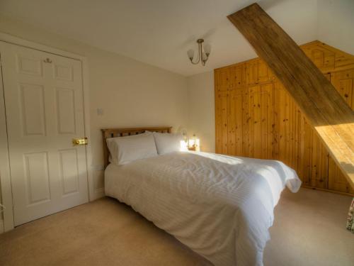 a bedroom with a white bed and wooden cabinets at Kings Head Cottage in Pickering