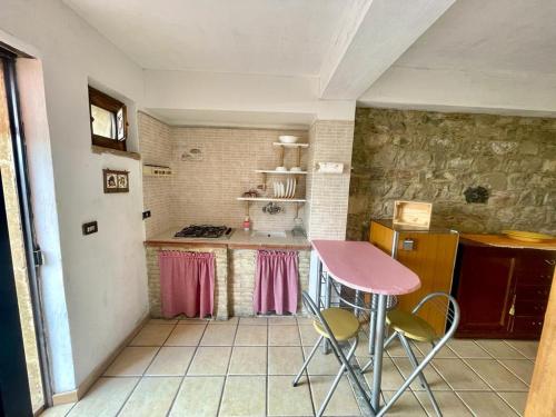 una pequeña cocina con mesa y sillas rosas en Casetta Girasole, en Centuripe