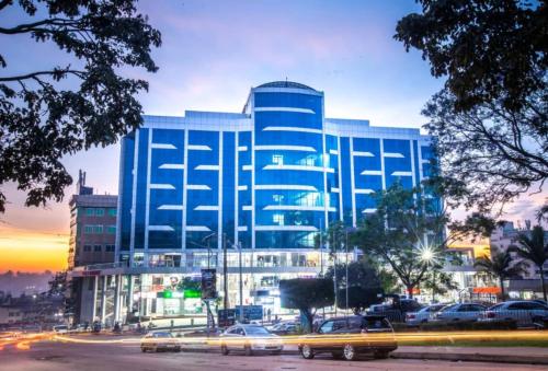 a large blue building with cars parked in front of it at Koki Hotel in Kampala