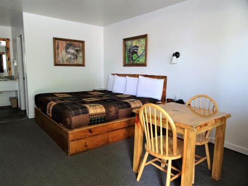 Eagle's Nest Motel في Priest River: غرفة نوم بسرير وطاولة وكراسي