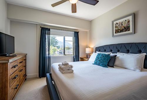 1 dormitorio con 1 cama, TV y ventana en Downunder Mountain Retreat by Revelstoke Vacations en Revelstoke