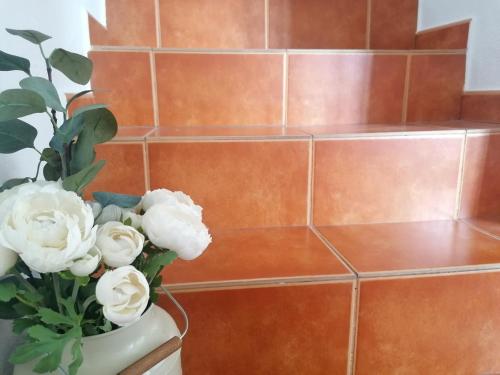 a vase with white flowers in front of a staircase at A Casa Pequenina - Escusa, Marvão in Marvão