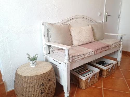 a white bench with pillows on it with baskets at A Casa Pequenina - Escusa, Marvão in Marvão