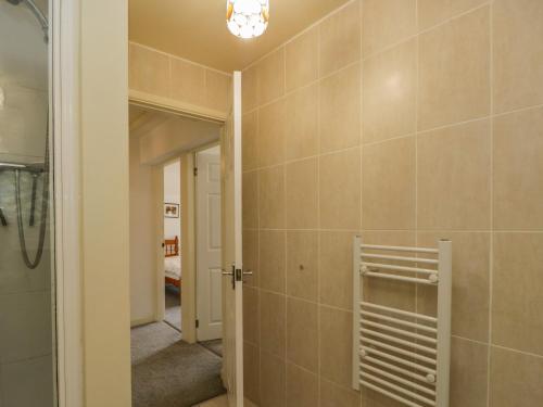 a bathroom with a shower and a tile wall at Newfield Apartment 1 in Broughton in Furness