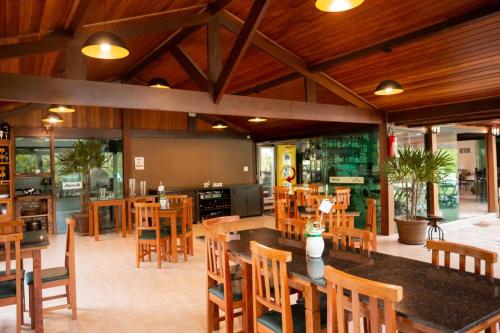 une salle à manger avec des tables et des chaises en bois dans l'établissement Pousada Maritacas do Sana, à Sana
