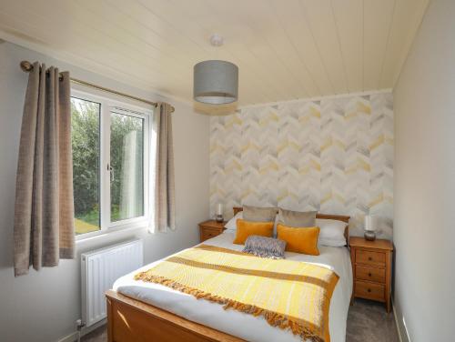 a bedroom with a bed with orange and yellow pillows at Fairview Lodge in Pwllheli