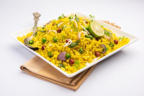 a plate of yellow rice with vegetables and a lime at Hotel laxminarayan in Shirdi