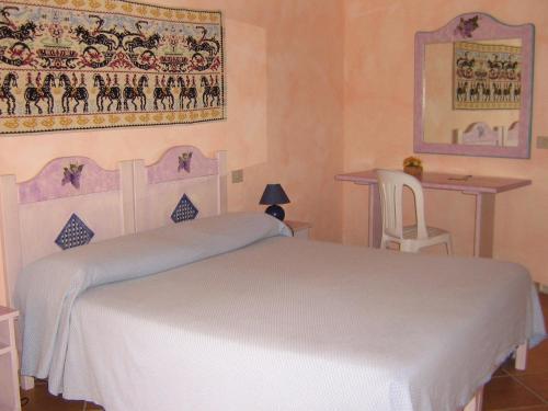 1 dormitorio con cama blanca y mesa en Hotel Turismo Rurale Montitundu, en Marina di Portisco
