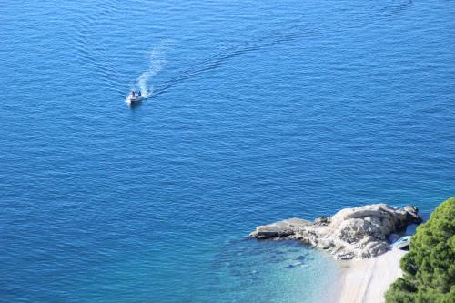 a boat in the water next to a small island at Apartments Villa Astra & Pinija in Brela