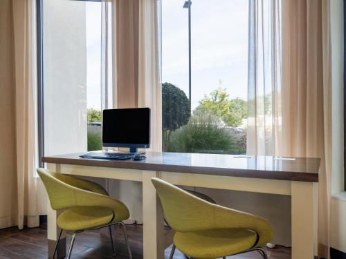 a computer sitting on a desk in front of a window at Holiday Inn Greensboro Coliseum by IHG in Greensboro