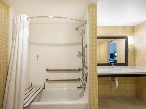 a bathroom with a bath tub and a sink at Holiday Inn Greensboro Coliseum, an IHG Hotel in Greensboro