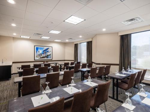 a conference room with tables and chairs and a projection screen at Holiday Inn Greensboro Coliseum by IHG in Greensboro