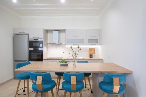 a kitchen with a wooden table and blue chairs at Luxury Villa Happynest in Spasméni Vrísi