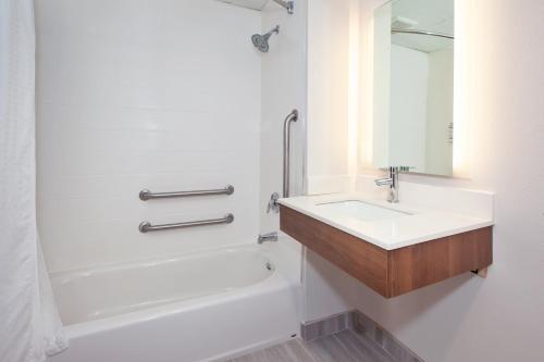 La salle de bains blanche est pourvue d'un lavabo et d'une baignoire. dans l'établissement Holiday Inn Express Hotel & Suites Warrenton, an IHG Hotel, à Warrenton