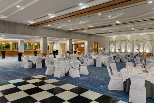 une salle de banquet avec des tables et des chaises blanches ainsi qu'un sol en damier dans l'établissement Crowne Plaza Dublin Airport by IHG, à Santry