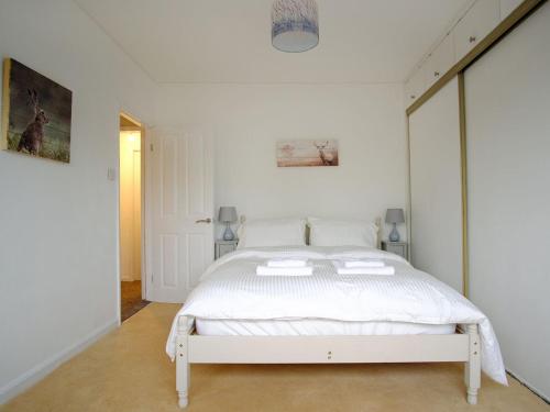 Un dormitorio blanco con una cama blanca. en Hobnail House en Staveley