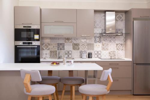 a kitchen with a white counter and stools at Luxury Villa Happynest in Spasméni Vrísi