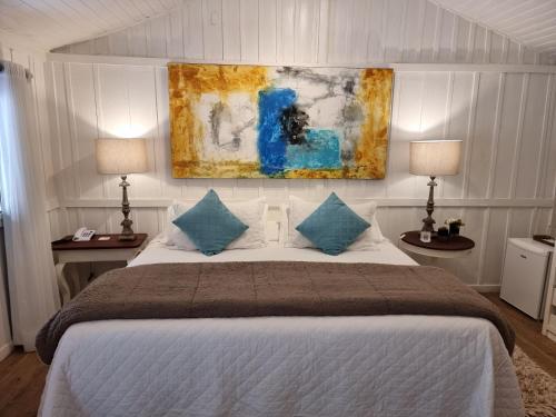 a bedroom with a bed with two lamps and a painting on the wall at Saison Resort & Spa in Itaipava