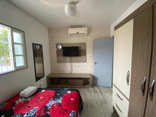 a bedroom with a bed and a tv in it at Casa na Praia da Pinheira in Palhoça