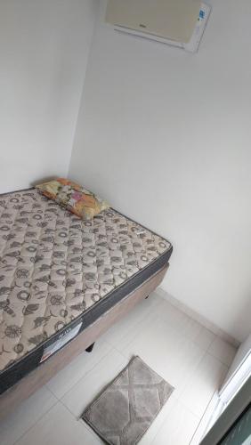 a bed sitting in a corner of a room at Apartamento Praia Grande -Canto do Forte in Praia Grande