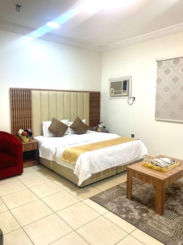 a bedroom with a large bed and a table at أسفار الأولى للشقق المخدومة in Al Multasa