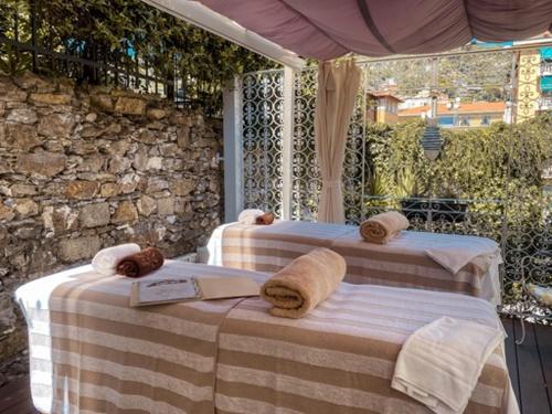 - un lit avec des serviettes et un livre sur une terrasse couverte dans l'établissement Hotel Sant'Andrea, à Santa Margherita Ligure