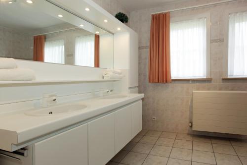 ein weißes Badezimmer mit einem Waschbecken und einem Spiegel in der Unterkunft Villa 't Uze in De Panne