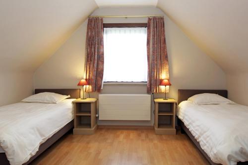 2 Betten in einem Schlafzimmer im Dachgeschoss mit Fenster in der Unterkunft Villa 't Uze in De Panne