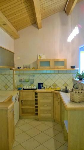 a large kitchen with wooden cabinets and tile floors at Gîte de groupe 15 à 19p, parc, salle de réception - CHAMBRES D'HOTES en semaine in Villeneuve-de-Berg