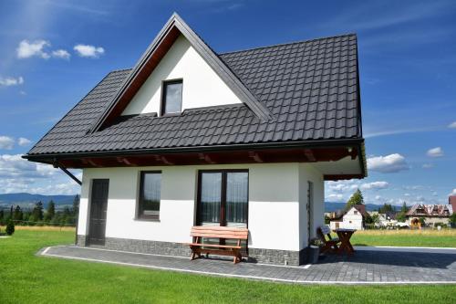 a small white house with a black roof at Domek u Zbyszka in Groń